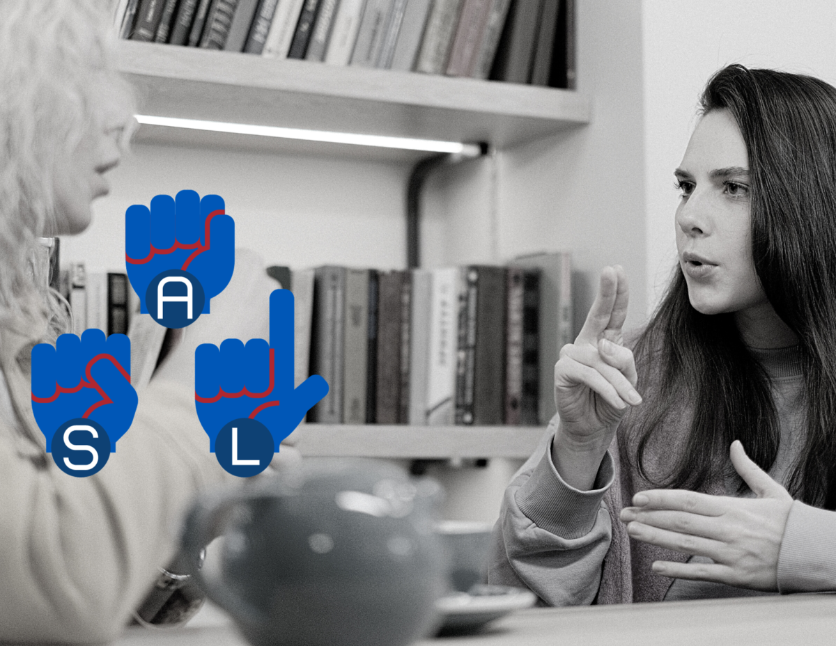 Two women sitting at a table near a bookshelf. They are having a conversation in ASL. Clip art hands in blue and red show the hand signs for the individual letters of A, S, L.